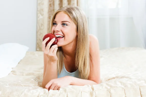 Kadın onu yatak ve yeme elma yatıyor — Stok fotoğraf