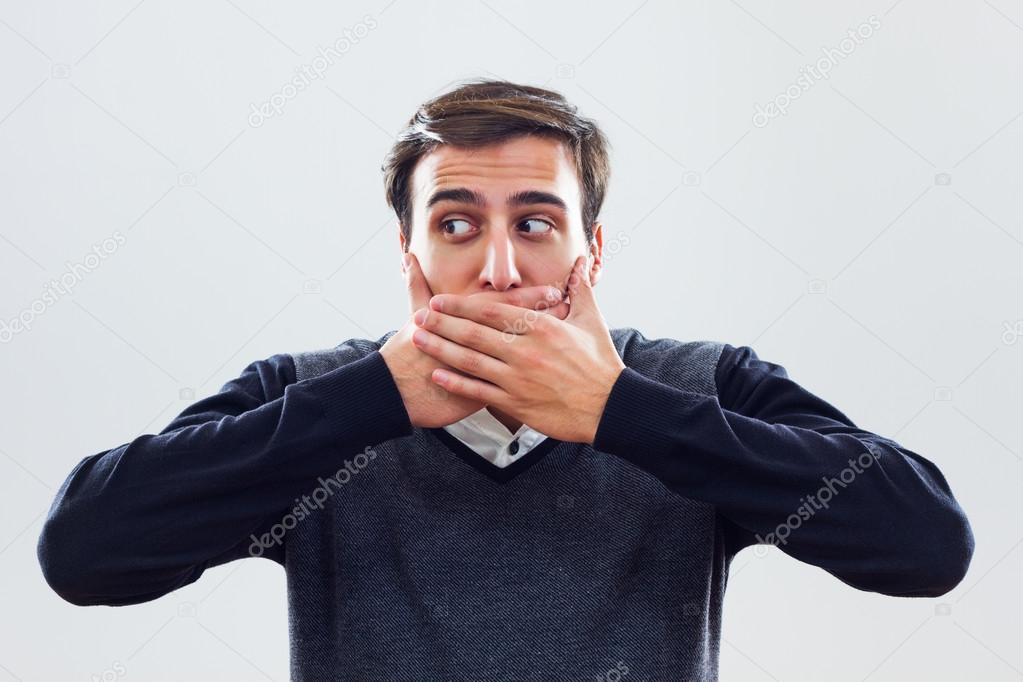 Young businessman covering mouth with hands