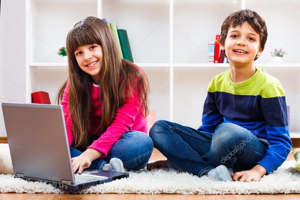 Cute little girl and little boy are using laptop