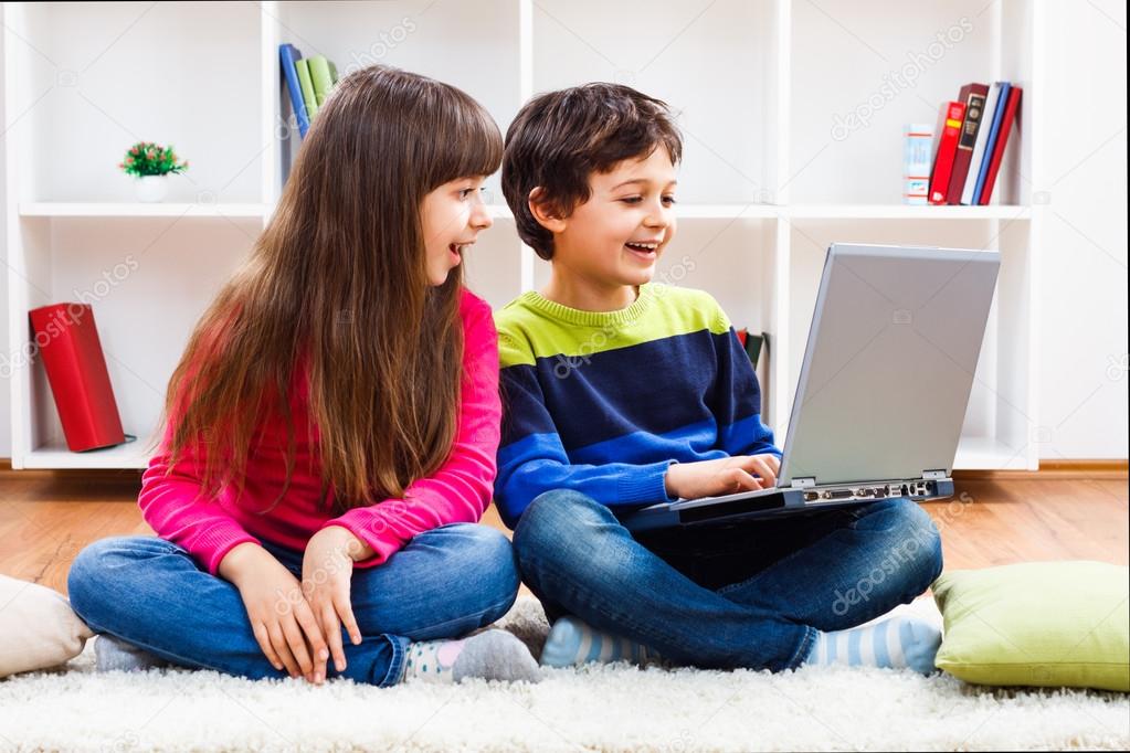 Cute little girl and little boy are using laptop