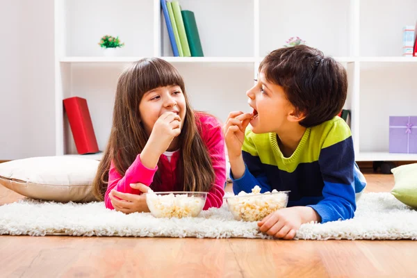 Liten flicka och pojke tycker om att äta popcorn — Stockfoto