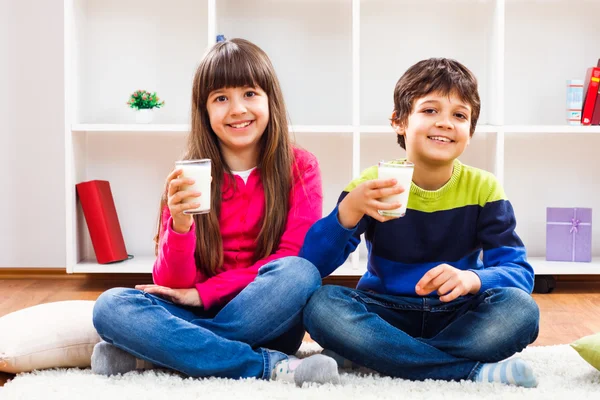 Schattig klein meisje en kleine jongen houden glas melk — Stockfoto