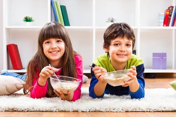 Söt liten flicka och pojke äter spannmål — Stockfoto