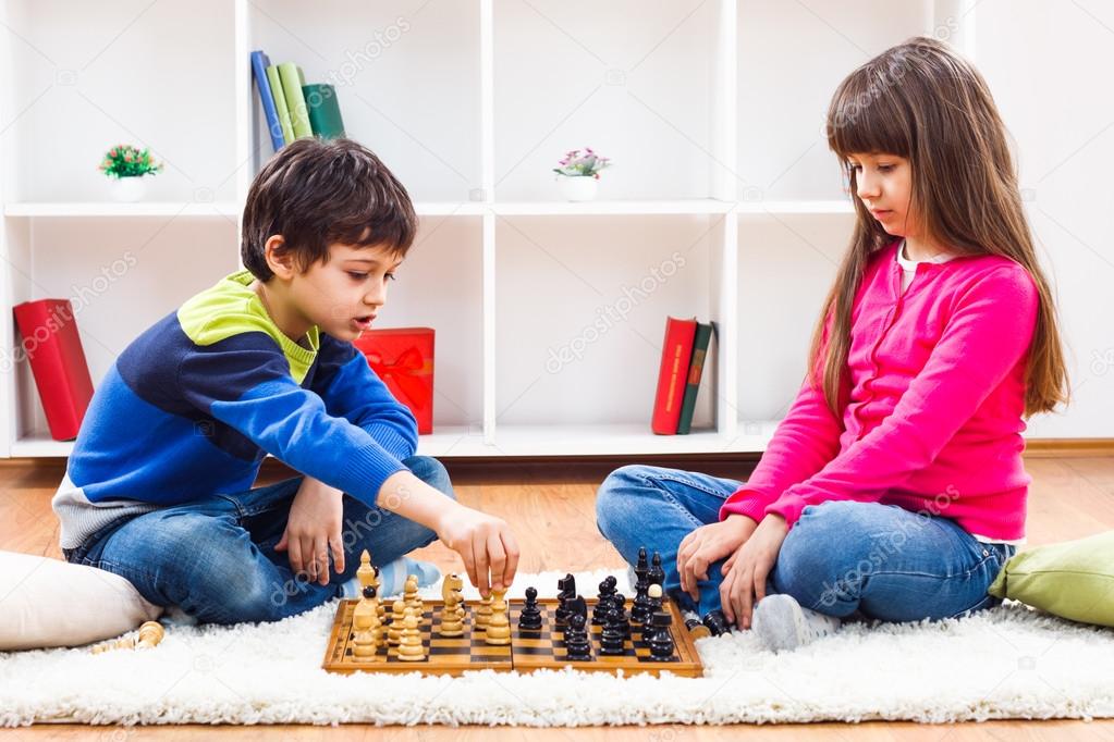 Little boy and little girl are playing chess