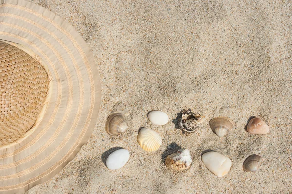 Strohhut, Muscheln und Felsen im Sand — Stockfoto