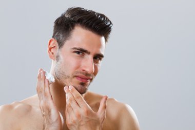 Handsome man applying shaving cream on his face clipart
