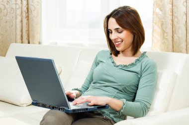 Woman sitting on sofa at her home and using laptop