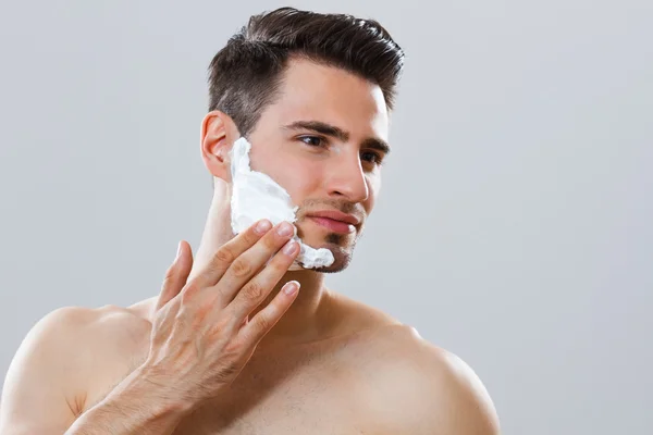 Yakışıklı adam yüzünü tıraş kremini uygulamadan — Stok fotoğraf