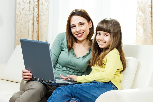 Madre e hija sentadas y usando laptop — Foto de Stock