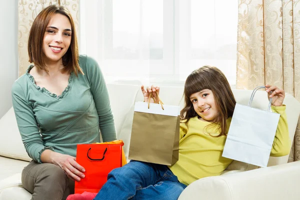 Mor og datter sitter på sofaen etter shopping. – stockfoto