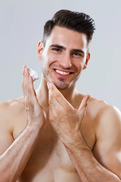 Schöner Mann, der Rasierschaum auf sein Gesicht aufträgt — Stockfoto