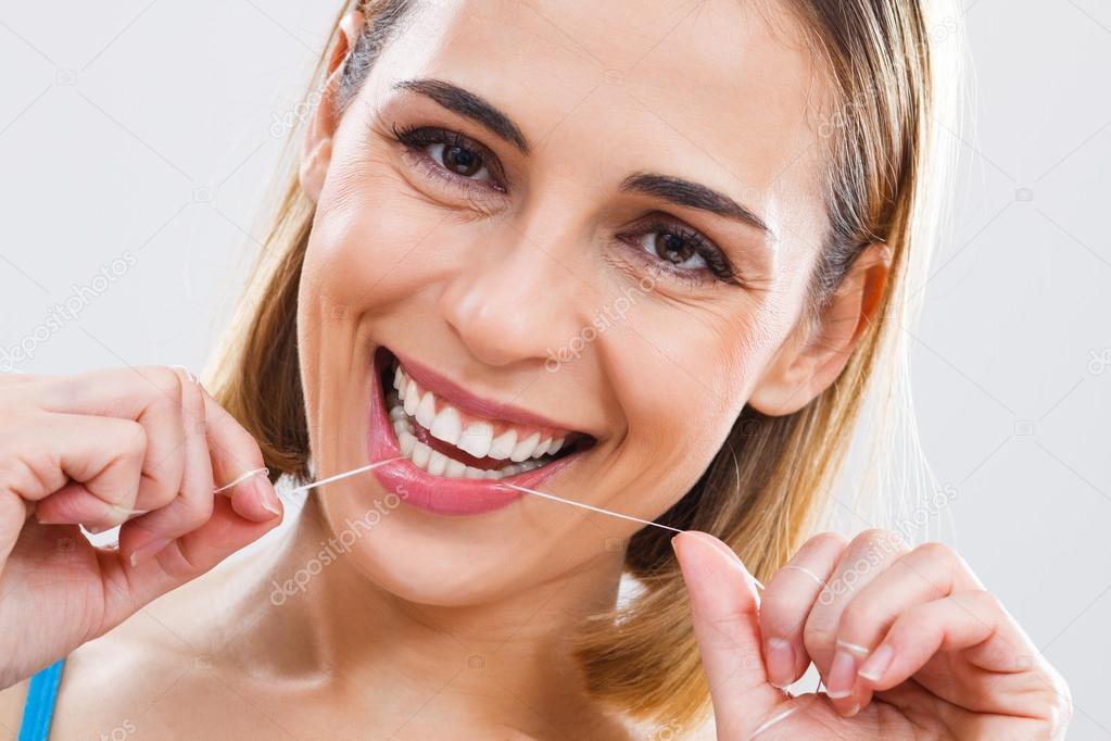 Beautiful woman using dental floss.