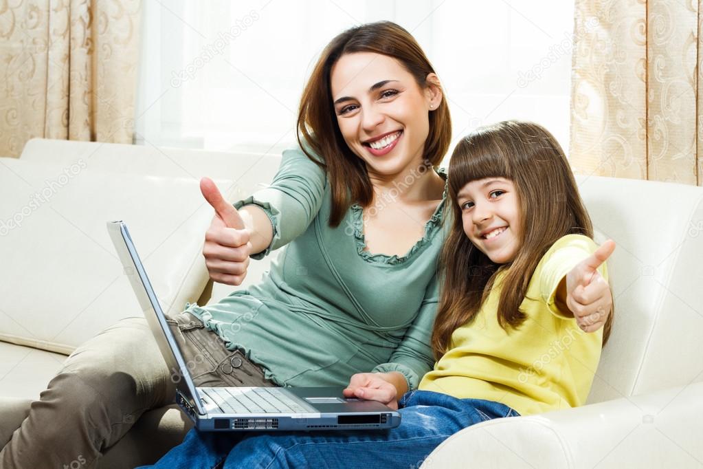 Mother and daughter sitting and using laptop