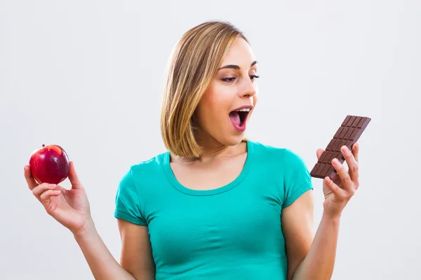 Frau hält Apfel und Schokolade in der Hand — Stockfoto