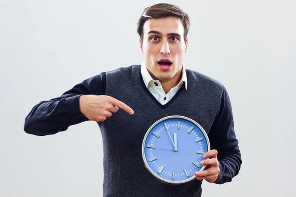 Разочарованный бизнесмен указывает на настенные часы — стоковое фото