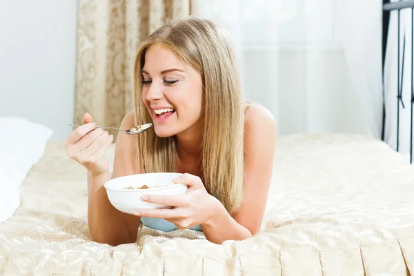 Woman is eating cereals with nuts for breakfast — Stock Photo, Image