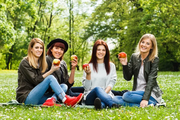 Девушки сидят в парке и держат яблоки — стоковое фото