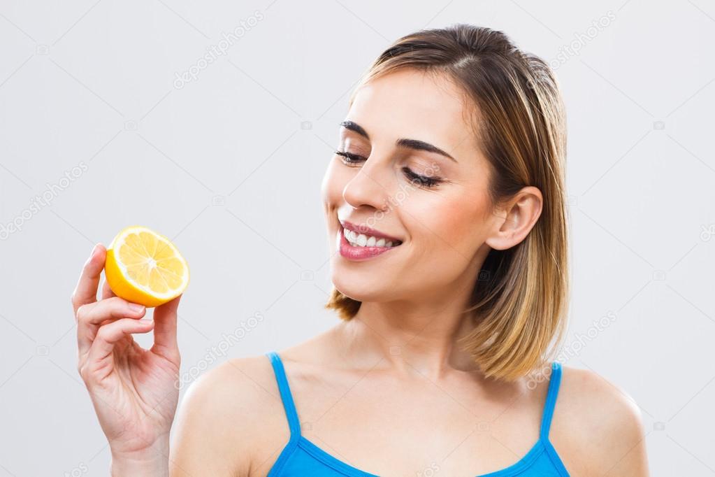 woman is holding slice of lemon