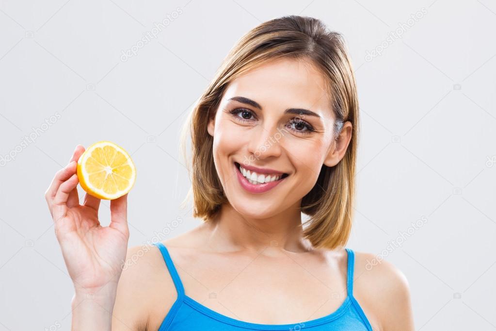 Woman holding slice of lemon