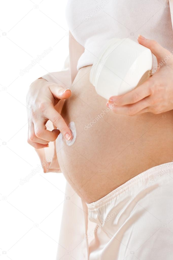 Pregnant woman applying moisturizer on her belly