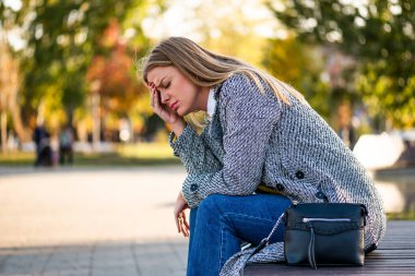 Şehir parkında bankta tek başına otururken başı ağrıyan ceketli bir iş kadınının portresi. Kariyeri ve kişisel sorunlarıyla ilgili baskı ve korkuyla uğraşıyor..