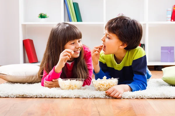 Pojke och flicka äter popcorn — Stockfoto