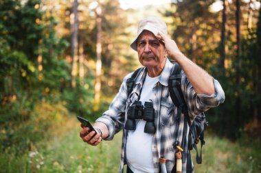 Dağda yürürken yol tarifi için akıllı telefon kullanan endişeli ve kaybolmuş bir yürüyüşçü..