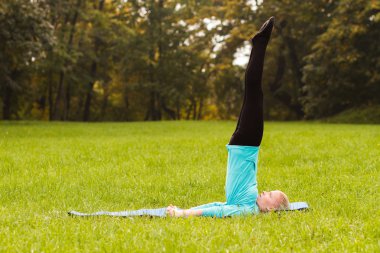 Kadın parkta yoga yapıyor.