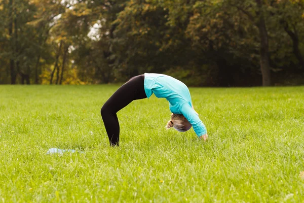 Kvinna som utövar yoga i parken — Stockfoto