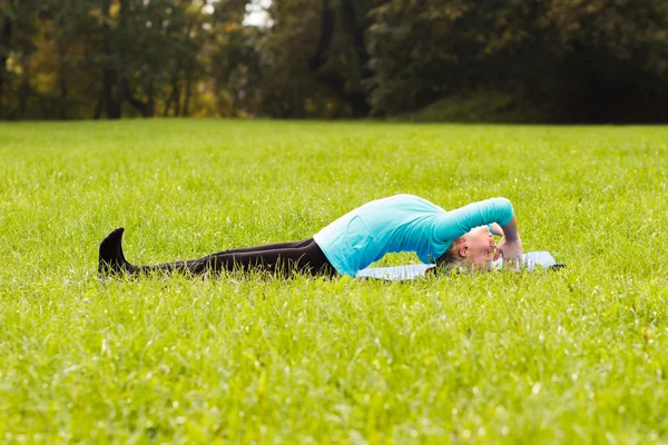 Kvinna som utövar yoga i parken — Stockfoto