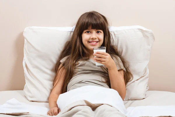 Mädchen im Bett trinkt Milch — Stockfoto