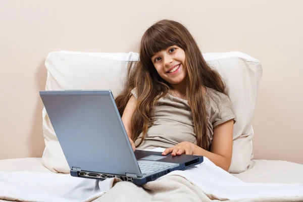 Dizüstü bilgisayar ile yatakta kız — Stok fotoğraf