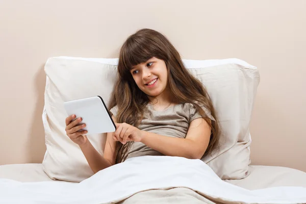 Flicka i sängen med hjälp av Tablet PC — Stockfoto