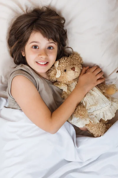 Mädchen im Bett mit Bärenspielzeug — Stockfoto