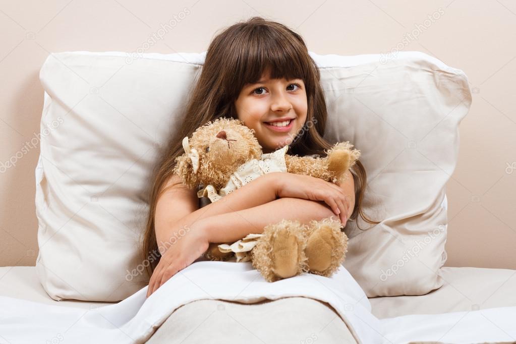 girl in bed with bear toy