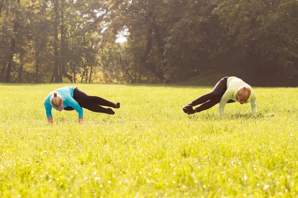 Vänner utövar yoga i park — Stockfoto