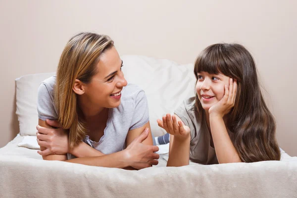 Mor och dotter talar på sängen — Stockfoto