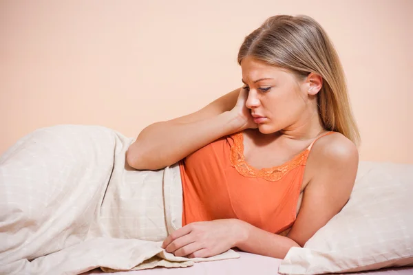 Traurige junge Frau im Bett — Stockfoto