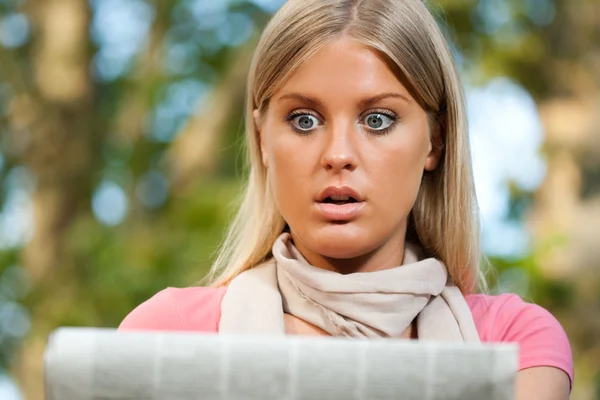 Shocked woman reading newspaper — Stock Photo, Image