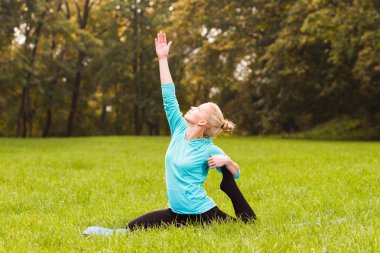 Kadın parkta yoga yapıyor.