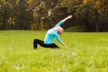 Kadın parkta yoga yapıyor.