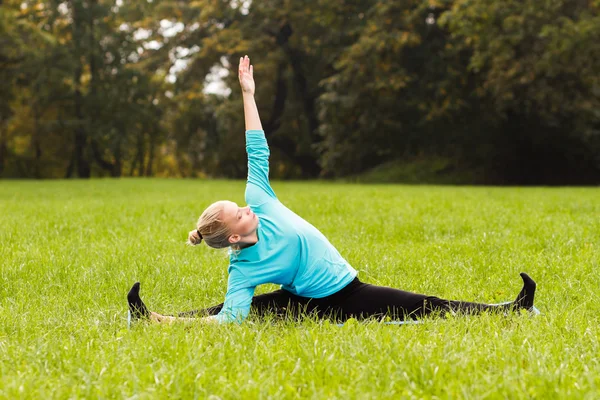 Kvinna som utövar yoga i parken — Stockfoto