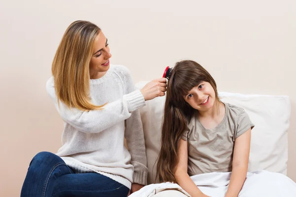 Mother combing daughters hair — Stock Photo, Image