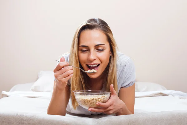 Vrouw in bed ontbijt eten — Stockfoto