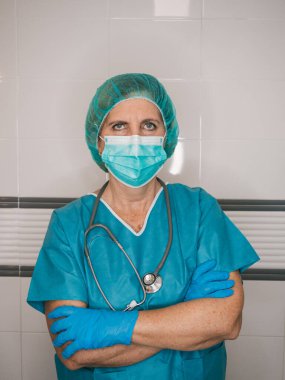 Portre sağlık uzmanı kadın maske ve bereli saçlara karşı korunuyor.