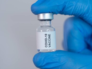 Covid-19 aşı şişesi bir sağlık çalışanının eldivenli ellerinden tutuldu.