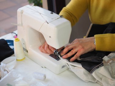 Evde dikiş makinası kullanan kadın elleri