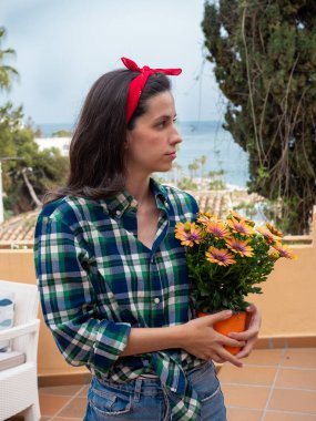 Güzel, genç bir kadın bahçeyle uğraşıyor saksılara çiçek dikiyor.