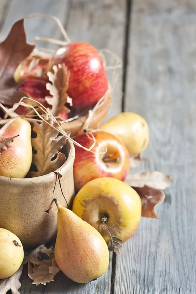 Peras y manzanas con hojas de otoño de fondo — Foto de Stock