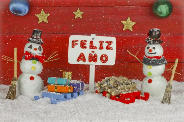 Two snowmen holding a sign with the words Happy New Year on spanish